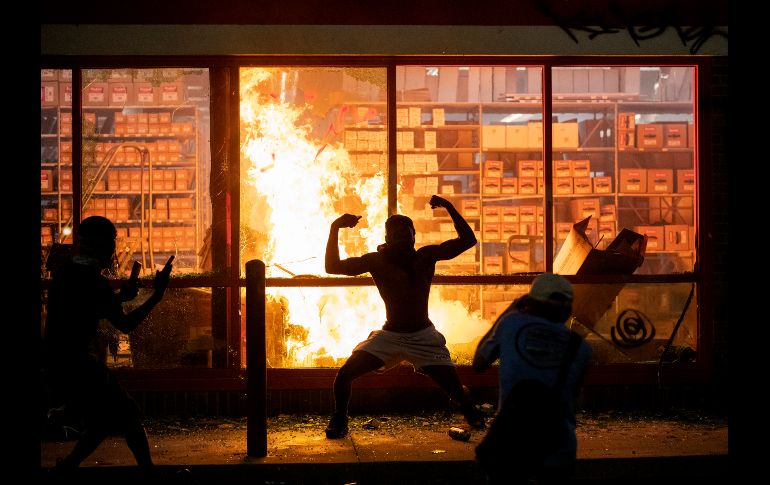Un manifestante posa frente a una tienda incendiada. AP/ Star Tribune/C. Gonzalez