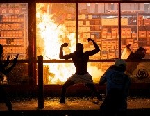 Un manifestante posa frente a una tienda incendiada. AP/ Star Tribune/C. Gonzalez