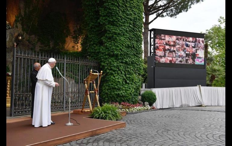 El Sumo Pontífice estaba sentado delante de la réplica de la cueva de Lourdes, meditando, de espaldas a los fieles, que guardaban una distancia de más de un metro entre sí. EFE/Vatican Media