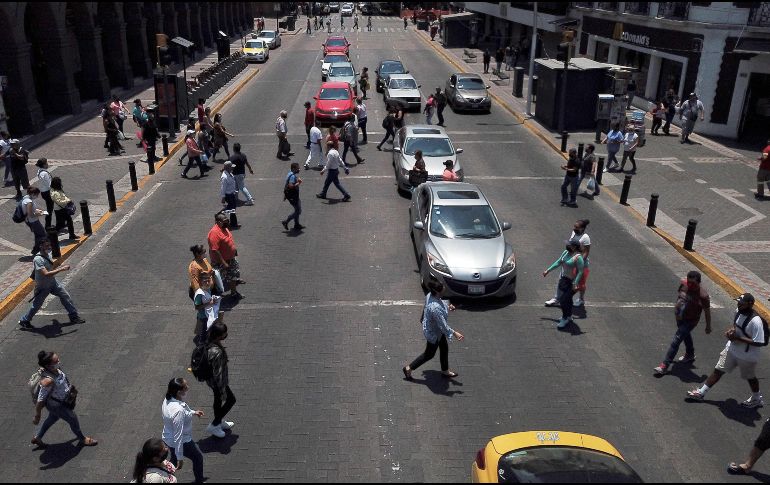 Movimiento de personas y autos este lunes en el Centro de Guadalajara, al reabrir algunos negocios tras la cuarentena. AFP/U. Ruiz