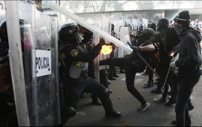 Manifestantes arremeten este viernes contra policías durante una protesta frente a la Embajada estadounidense, en la Ciudad de México. EFE/J. Pazos