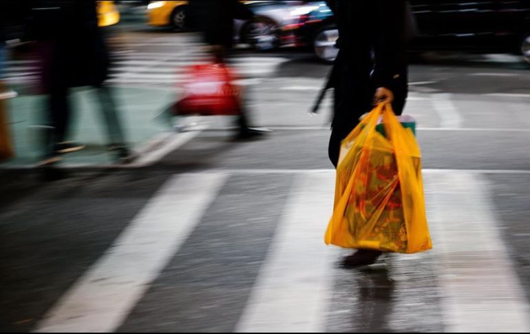Personas cargan bolsas con sus compras afuera de un centro comercial en Nueva York. EFE/A. Vigaray