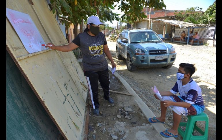Con el alumno a dos metros de distancia, Espinoza coloca la pizarra donde puede y repite la clase que horas antes había impartido por Zoom. EFE/M. Pin