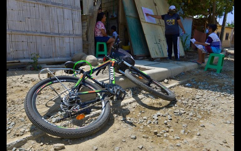 Con el alumno a dos metros de distancia, Espinoza coloca la pizarra donde puede y repite la clase que horas antes había impartido por Zoom. EFE/M. Pin
