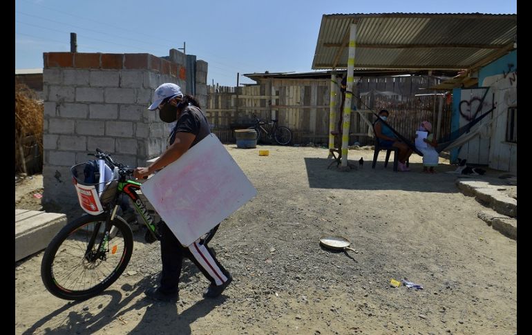 Con el alumno a dos metros de distancia, Espinoza coloca la pizarra donde puede y repite la clase que horas antes había impartido por Zoom. EFE/M. Pin