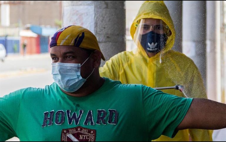 Un trabajador sanitario desinfecta a un grupo de personas antes de entrar a un local comercial, en Maracaibo, Venezuela. EFE/H. Chirinos