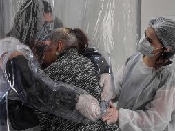 La cortina está equipada con grandes bolsillos para que los visitantes y residentes puedan deslizar sus brazos. Suzane Valverde (i) con su madre Carmelita Valverde, de 85. AFP/N. Almeida