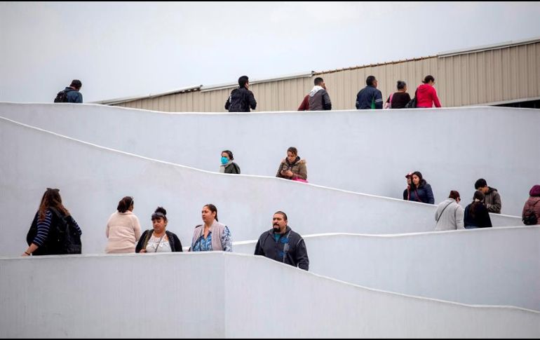 Un grupo de migrantes espera para iniciar la solicitud de visa humanitaria afuera de la oficina fronteriza estadounidense de El Chaparral, en Tijuana, Baja California. EFE/A. Rochin