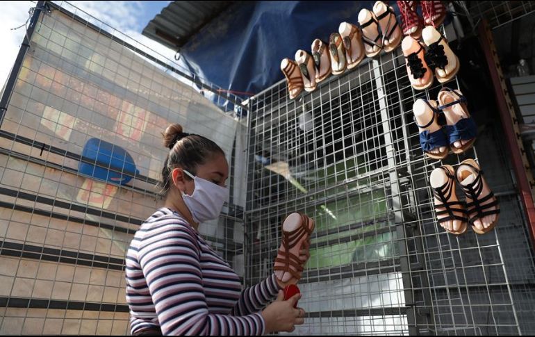 Tatiana Nolasco acomoda este martes su mercadería en una venta de zapatos en el centro de San Salvador. EFE/R. Sura