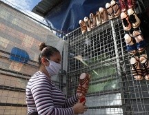Tatiana Nolasco acomoda este martes su mercadería en una venta de zapatos en el centro de San Salvador. EFE/R. Sura