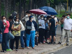 Personas con síntomas de COVID-19 hacen hoy fila para recibir atención en el centro de triaje del Instituto Nacional de Formación Profesional, en Tegucigalpa. AFP/O. Sierra