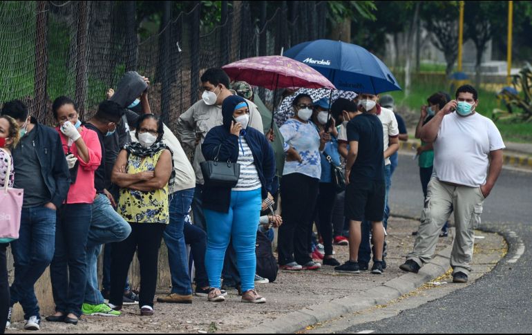 Personas con síntomas de COVID-19 hacen hoy fila para recibir atención en el centro de triaje del Instituto Nacional de Formación Profesional, en Tegucigalpa. AFP/O. Sierra