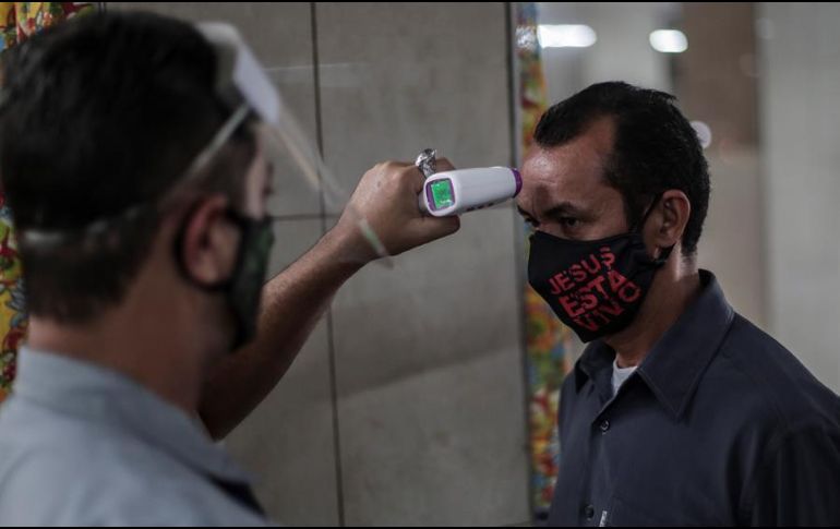 Un guardia mide la temperatura a un hombre que entra al Mercadao de Madureira, durante la segunda semana de reactivación decretada por el Gobierno local, en el norte de Río de Janeiro. EFE/A. Lacerda