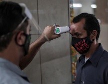 Un guardia mide la temperatura a un hombre que entra al Mercadao de Madureira, durante la segunda semana de reactivación decretada por el Gobierno local, en el norte de Río de Janeiro. EFE/A. Lacerda