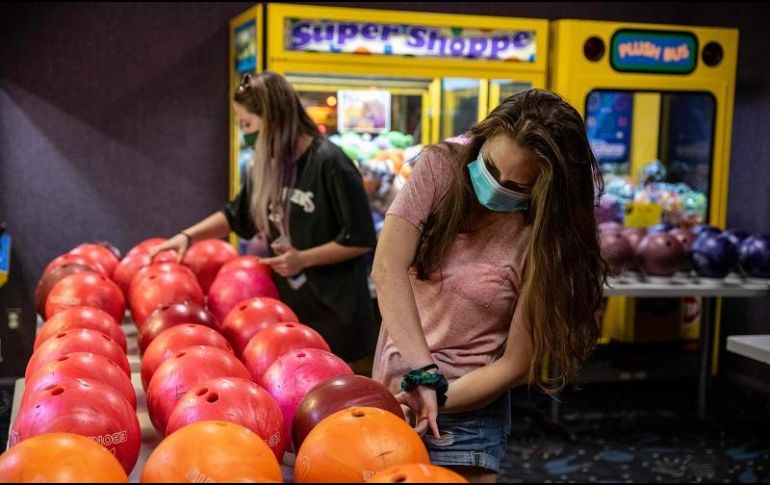 Jóvenes recogen bolas limpias en un boliche de Westgate Lanes en Austin, Texas. Los comercios no esenciales cerrarán sus puertas nuevamente ante el repunte de infecciones. AFP/S. Flores