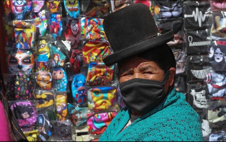 Una mujer aymara camina cerca de un puesto de cubrebocas de tela en La Paz, Bolivia. EFE/M. Alipaz