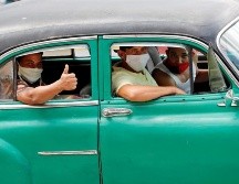 Varias personas con tapabocas pasean en un auto clásico por calles de La Habana. EFE/E. Mastrascusa