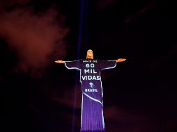 La estatua del Cristo Redentor en Río de Janeiro se ilumina en un homenaje a las personas fallecidas por COVID-19. AFP/M. Pimentel