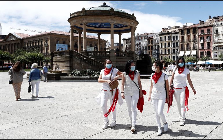 Personas con la vestimenta típica de los Sanfermines pasean por una desolada plaza en Pamplona hoy, fecha en la que deberían comenzar los Sanfermines del 2020 y que fueron suspendidos por la pandemia. EFE/J.Diges