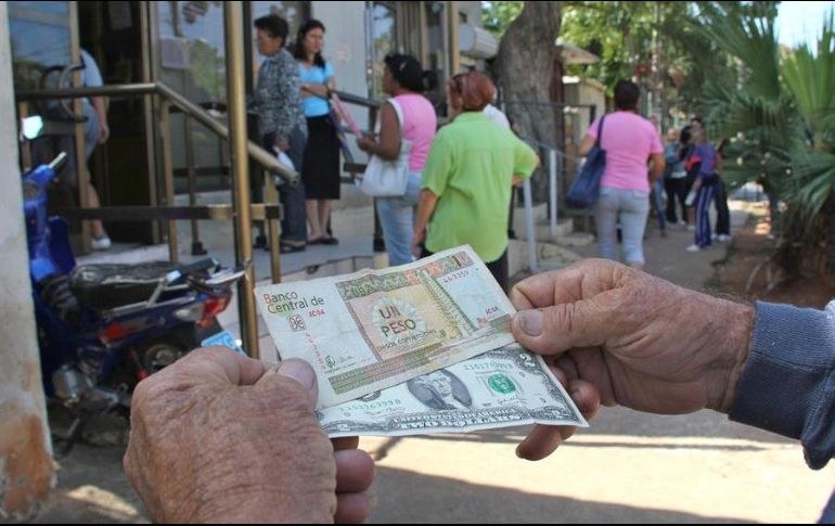 Un hombre muestra un peso convertible cubano y un dólar estadounidense. EFE/ARCHIVO