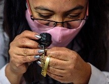 Una trabajadora del Nacional Monte de Piedad hace una valuación de una pieza de joyería de oro. AFP/P. Pardo