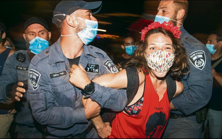 Arresto. Oficiales someten a una manifestante de las protestas afuera de la residencia del premier. AP