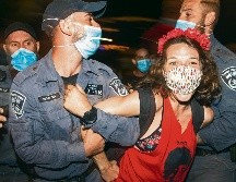 Arresto. Oficiales someten a una manifestante de las protestas afuera de la residencia del premier. AP