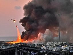 Un helicóptero combate las llamas tras una explosión. AFP