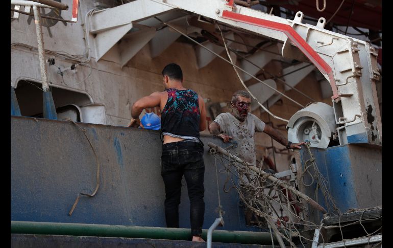Personas salen de una embarcación anclada en el puerto. AP/ H. Malla