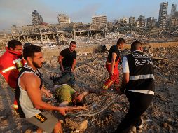 Bomberos evacuan a un herido de la zona de la explosión en el puerto. AFP/A. Amro