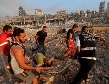 Bomberos evacuan a un herido de la zona de la explosión en el puerto. AFP/A. Amro
