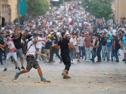 Libaneses que culpan a las autoridades de negligencia por la mortal explosión, protestan este domingo ante fuerzas de seguridad en Beirut. AFP/J. Eid