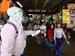 Una empleada de la salud ofrece gel antibacterial a personas en un mercado de la Ciudad de México. EFE/J. Núñez