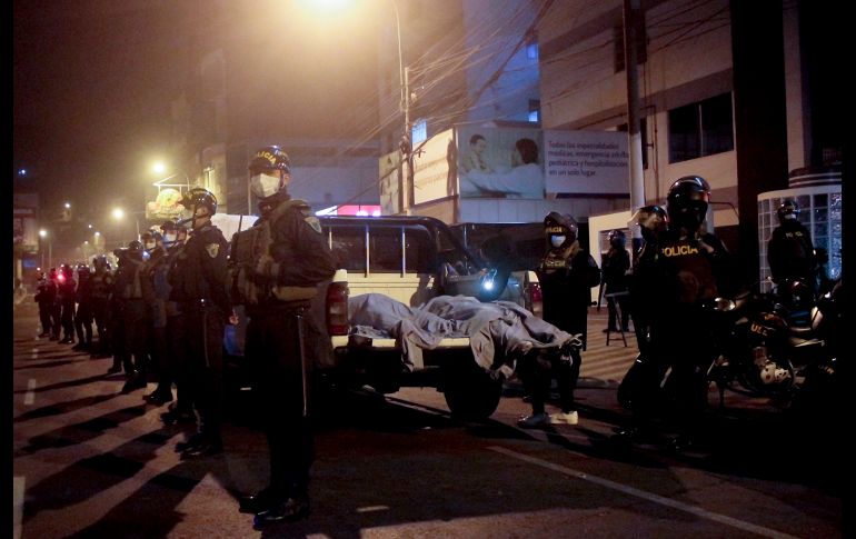 Oficiales vigilan junto a cuerpos afuera de la discoteca en Lima. AP/D. Vertiz