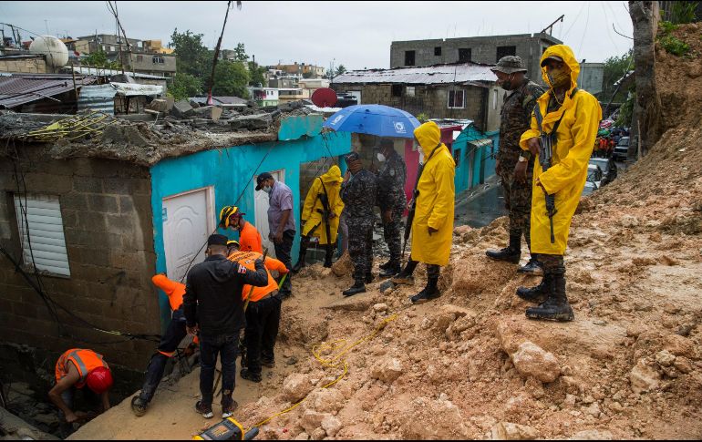 Miembros de la Defensa Civil intentan rescatar el cuerpo de un niño que murió junto a su madre tras el derrumbe de su casa, este domingo en Santo Domingo, República Dominicana. EFE/ O. Barría