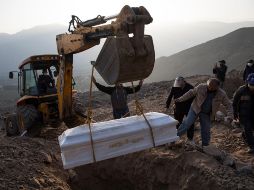 Una excavadora coloca el ataúd con los restos de una víctima de coronavirus en un cementerio en Lima. AP/ARCHIVO