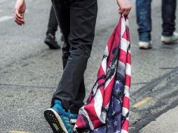 Un manifestante arrastra una bandera de los Estados Unidos durante una protesta después de la visita del presidente Donald Trump en Kenosha. EFE/T. Maury
