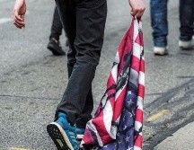 Un manifestante arrastra una bandera de los Estados Unidos durante una protesta después de la visita del presidente Donald Trump en Kenosha. EFE/T. Maury