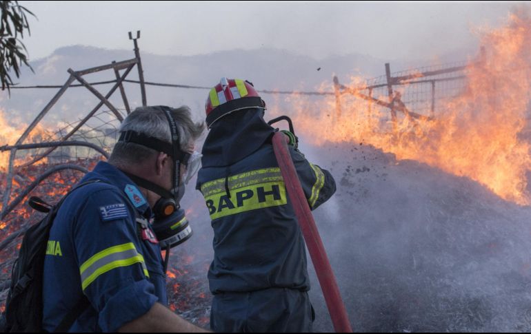 Bomberos rocían agua para apagar el incendio, en Anavissos, una aldea a la orilla del mar en el sur de Attica, en Atenas, Grecia. XINHUA/M. Lolos