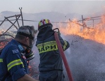 Bomberos rocían agua para apagar el incendio, en Anavissos, una aldea a la orilla del mar en el sur de Attica, en Atenas, Grecia. XINHUA/M. Lolos