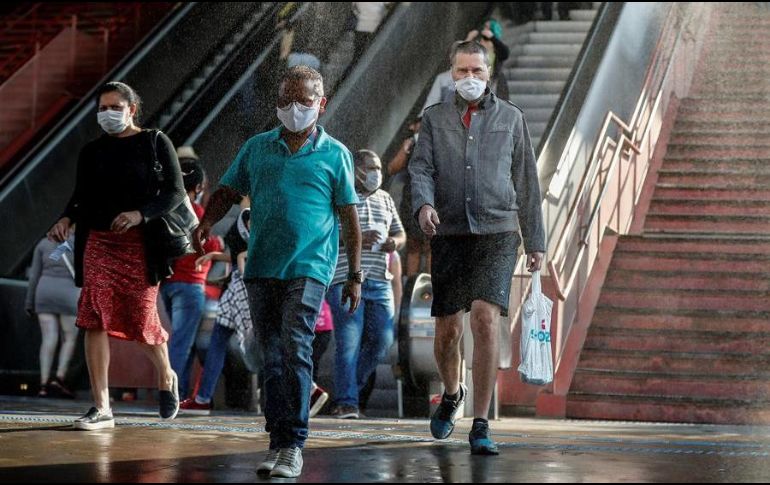 Usuarios pasan por una cabina de desinfección mientras salen de una estación del metro. EFE/S. Moreira