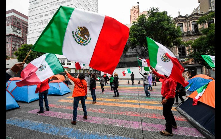 Manifestantes ondean banderas de México en el plantón en el centro de Ciudad de México. AFP/P. Pardo