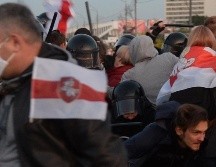 Policías antidisturbios con pasamontañas detuvieron a manifestantes y los llevaron a furgones. EFE
