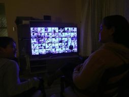 Una madre y su hijo siguen la transmisión a través de un televisor de la octava versión del homenaje de amor colectivo 