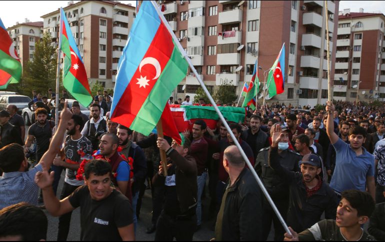Personas cargan banderas azerbaiyanas en el funeral de un militar presuntamente muerto en combate. AP/A. Karimov