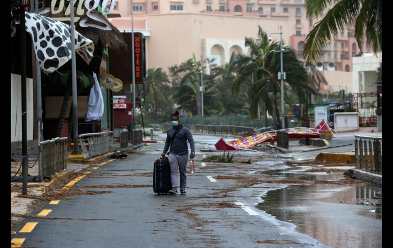Un turista camina hoy entre los escombros causados por el paso del huracán 