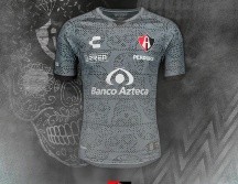 El traje es color gris y negro, con un estampado de calaveras de dulce, tradicionales del Día de Muertos. TWITTER / @atlasfc