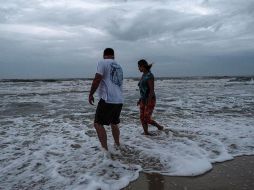 Dos personas caminan en la playa cuando el huracán 
