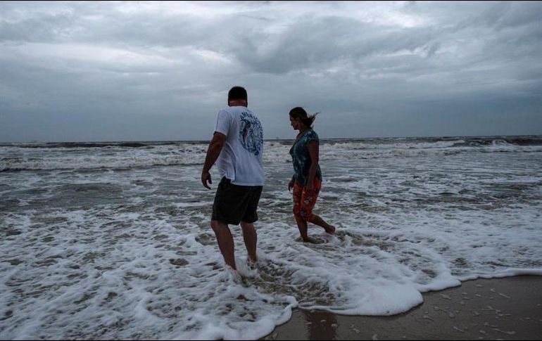 Dos personas caminan en la playa cuando el huracán 