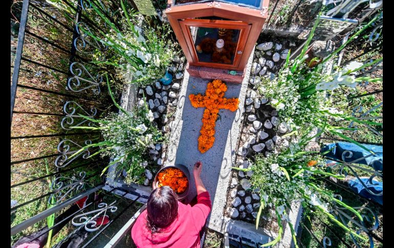 Una mujer decora este domingo la tumba de un familiar en el panteón Magdalena en  San Pedro Cholula, Puebla. Autoridades locales restringieron los horarios y el números de visitantes a los cementerios. AFP/P. Pardo